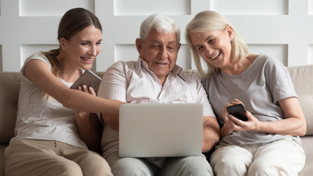 Older parents and adult children sitting together, looking at a laptop for dementia care resources and support information